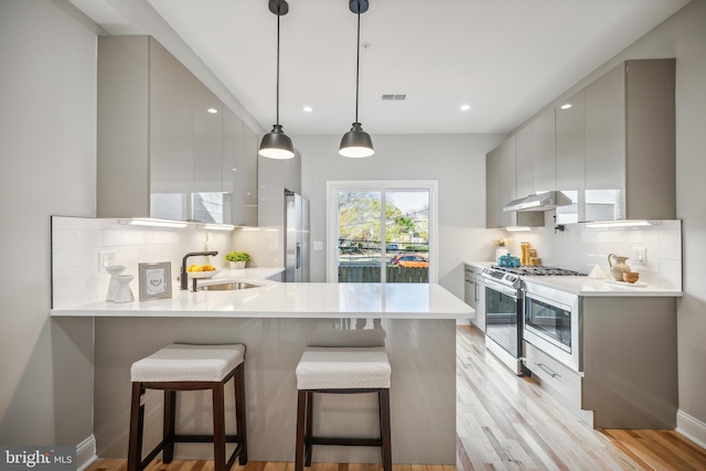 kitchen with kitchen peninsula, decorative backsplash, pendant lighting, and appliances with stainless steel finishes