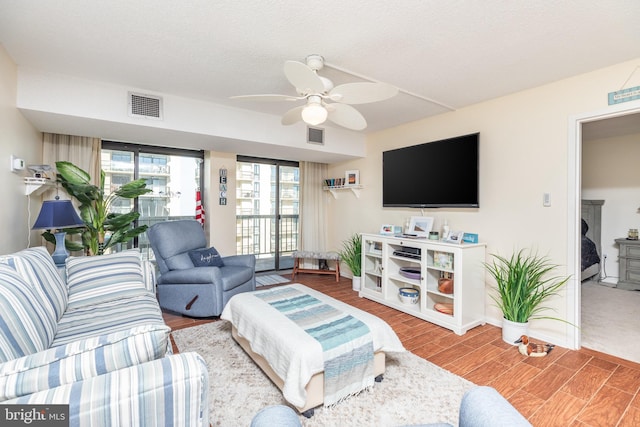 living room with a textured ceiling, ceiling fan, and wood-type flooring