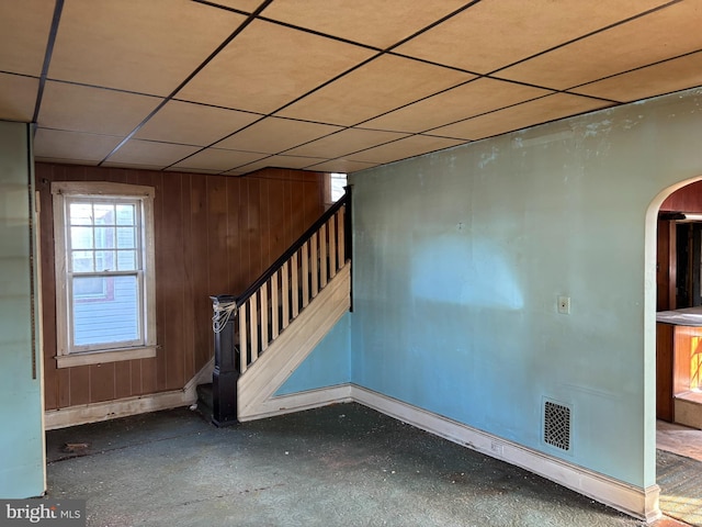 spare room featuring wood walls and a drop ceiling