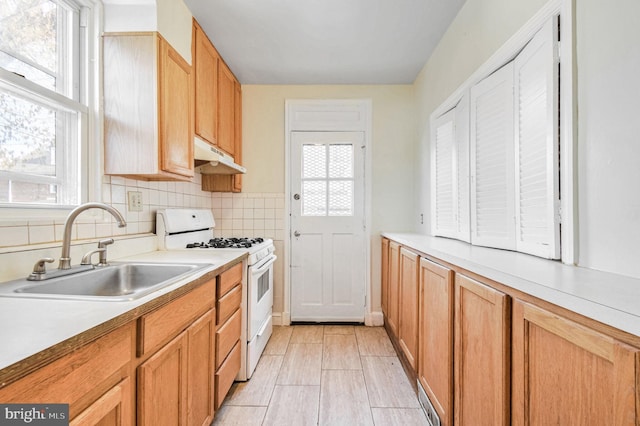 kitchen with tasteful backsplash, white gas range, sink, and a healthy amount of sunlight