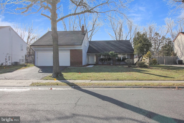 view of front of house with a garage, central air condition unit, and a front yard