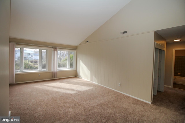 carpeted spare room with high vaulted ceiling