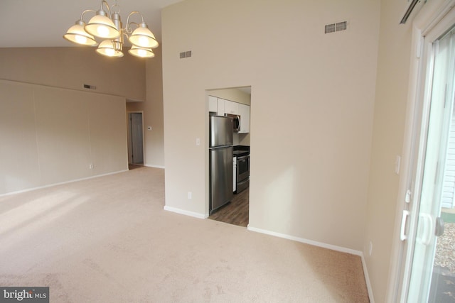 empty room with carpet floors, high vaulted ceiling, and a chandelier