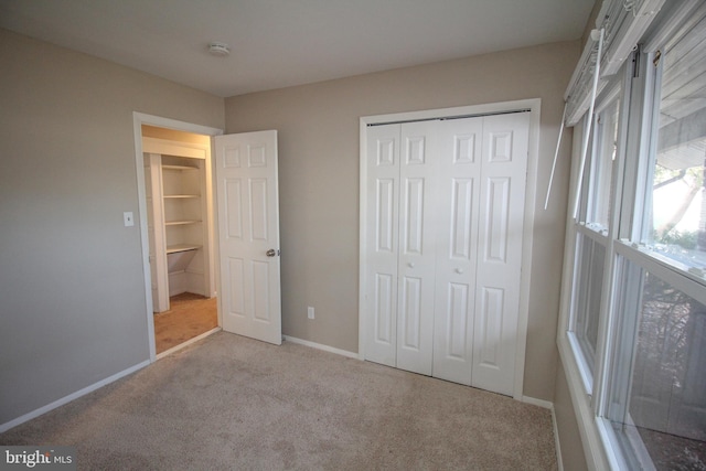 unfurnished bedroom with light colored carpet and a closet