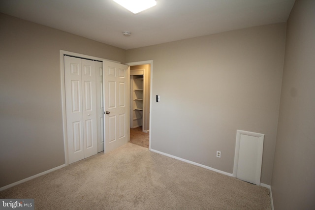 unfurnished bedroom featuring light carpet and a closet