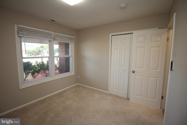 unfurnished bedroom featuring light carpet and a closet