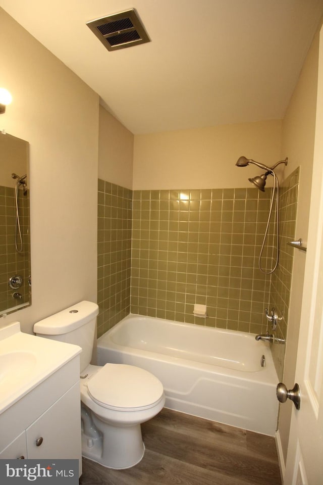 full bathroom featuring hardwood / wood-style floors, vanity, toilet, and tiled shower / bath