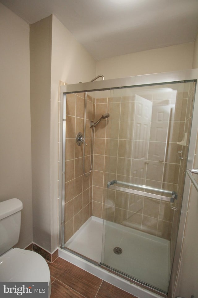 bathroom with a shower with door and toilet