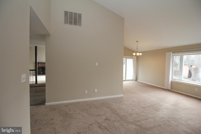 spare room with carpet flooring, a notable chandelier, and high vaulted ceiling