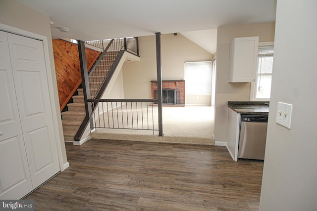 kitchen featuring white cabinets, dishwasher, dark wood-type flooring, and a brick fireplace