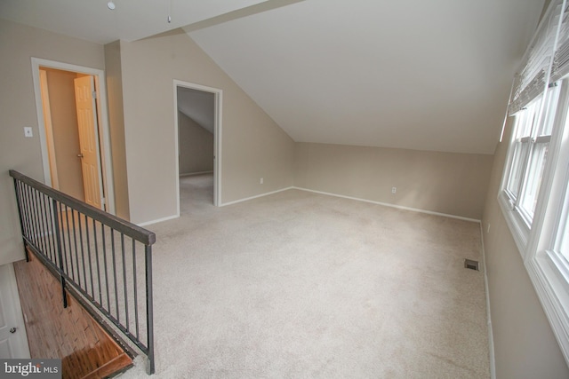 additional living space featuring light carpet and vaulted ceiling