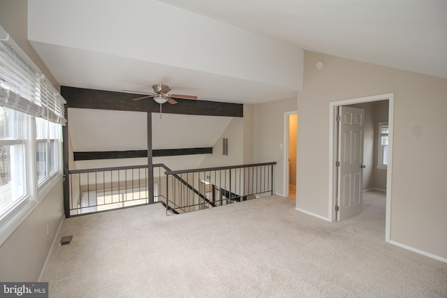 carpeted spare room featuring lofted ceiling with beams and ceiling fan