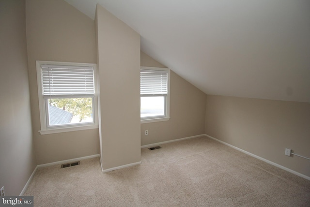 bonus room with light carpet and vaulted ceiling