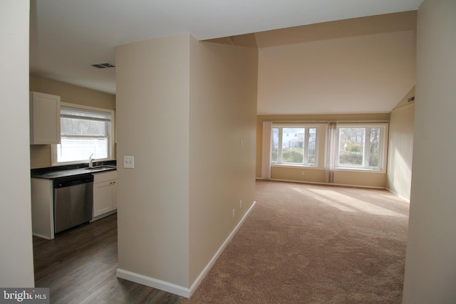 corridor with sink, lofted ceiling, and dark colored carpet