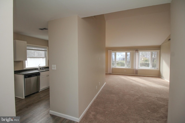 hall with dark carpet, lofted ceiling, and sink