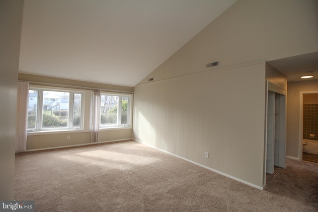 spare room featuring carpet flooring and high vaulted ceiling