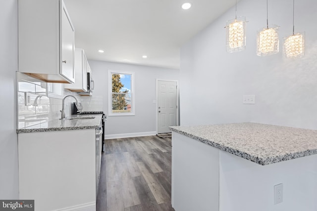 kitchen featuring white cabinetry, decorative light fixtures, sink, backsplash, and hardwood / wood-style floors