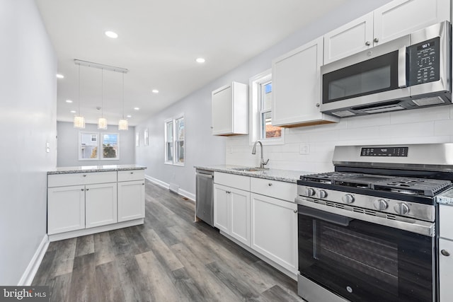 kitchen with sink, appliances with stainless steel finishes, white cabinets, and pendant lighting