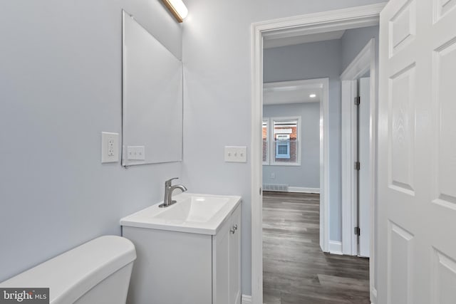 bathroom with toilet, vanity, and hardwood / wood-style floors