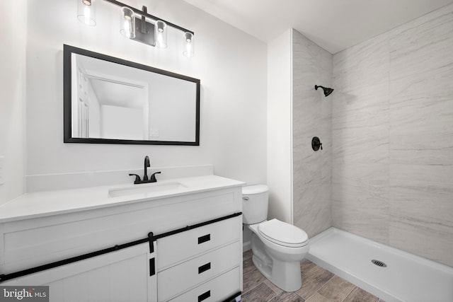 bathroom featuring tiled shower, vanity, and toilet