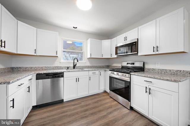 kitchen with stainless steel appliances, white cabinets, sink, and dark hardwood / wood-style floors