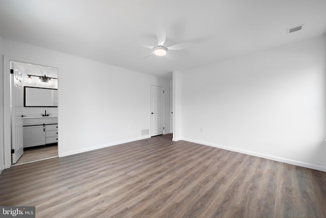 unfurnished bedroom with ceiling fan, ensuite bath, and wood-type flooring