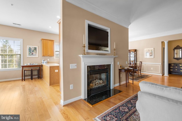 living room with ornamental molding, a high end fireplace, light hardwood / wood-style flooring, and ornate columns