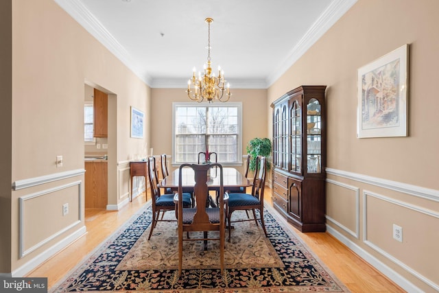 dining room featuring an inviting chandelier, crown molding, and light wood-type flooring