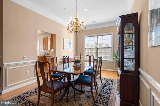 dining room with ornamental molding, hardwood / wood-style floors, and an inviting chandelier