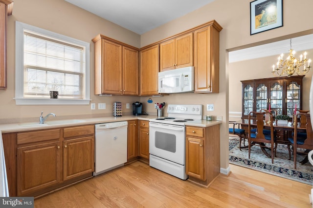 kitchen with pendant lighting, sink, light wood-type flooring, white appliances, and an inviting chandelier