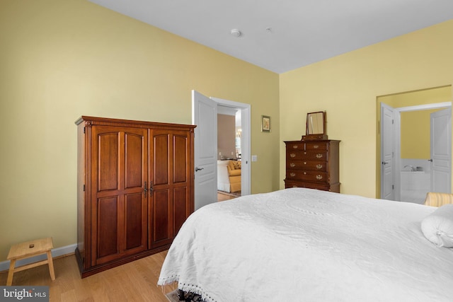 bedroom featuring connected bathroom and light hardwood / wood-style floors