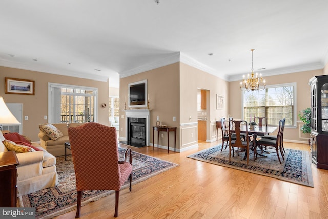 living room featuring crown molding, a healthy amount of sunlight, and light hardwood / wood-style flooring