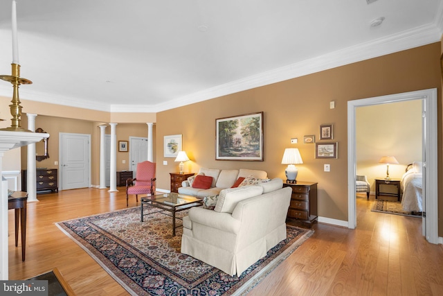 living room featuring ornate columns, ornamental molding, and light wood-type flooring