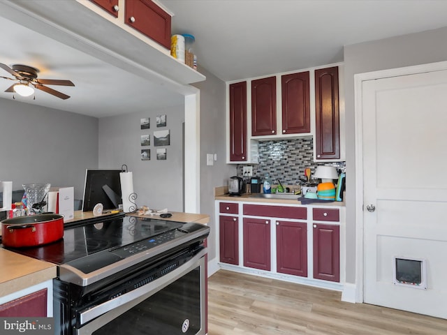 kitchen featuring electric range, light wood-type flooring, ceiling fan, decorative backsplash, and sink