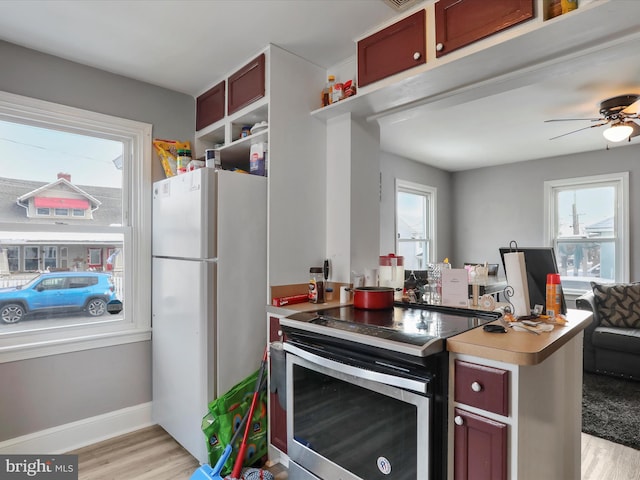 kitchen with stainless steel range with electric stovetop, light hardwood / wood-style floors, a wealth of natural light, and white fridge