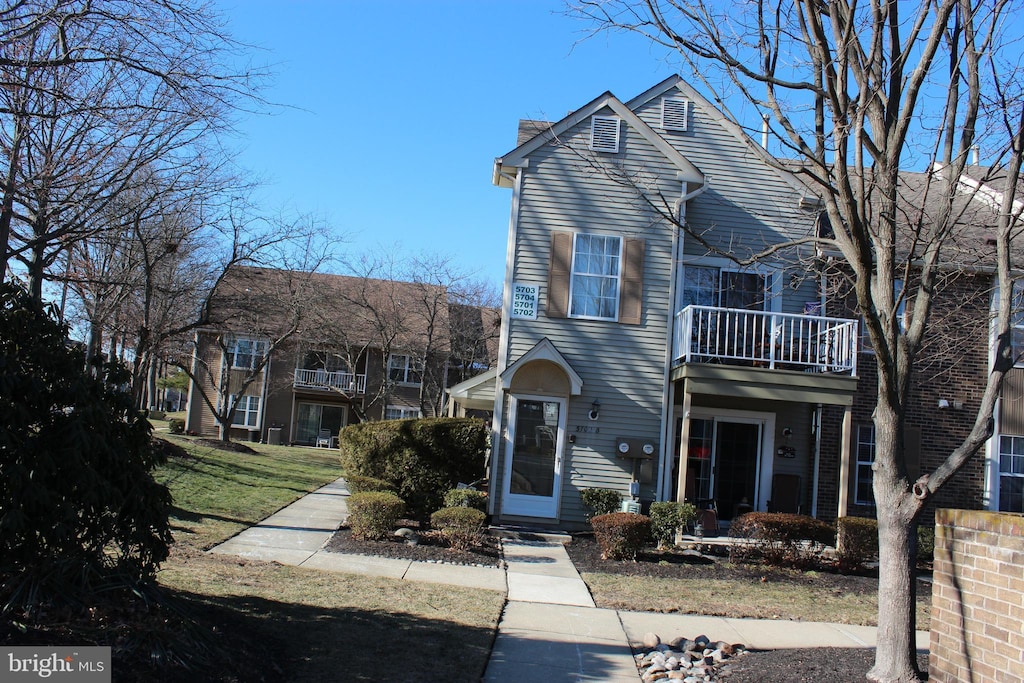 front facade with a balcony and a front yard