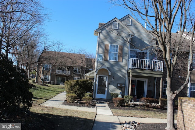 front facade with a balcony and a front yard