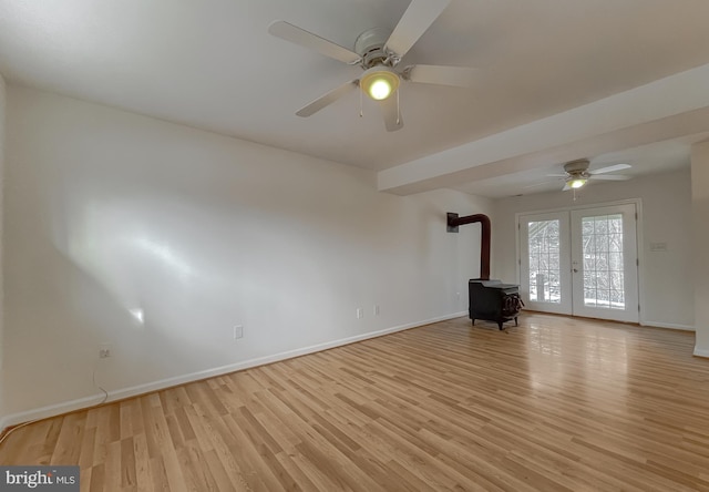 unfurnished living room with ceiling fan, french doors, a wood stove, and light hardwood / wood-style floors