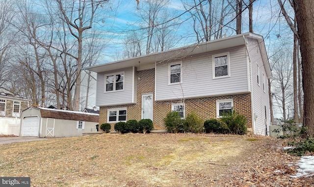 bi-level home featuring a front yard, a garage, and an outbuilding