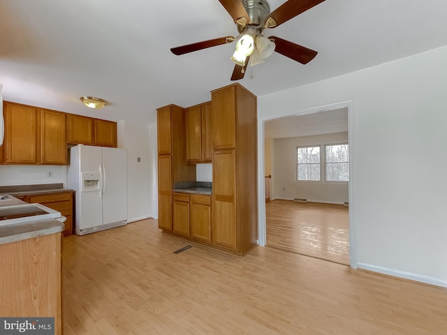 kitchen featuring ceiling fan, white fridge with ice dispenser, and light wood-type flooring