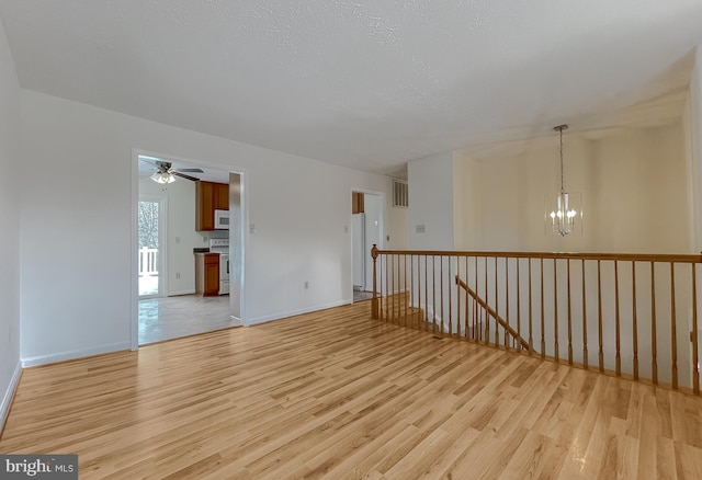 unfurnished room with a textured ceiling, light hardwood / wood-style floors, and a notable chandelier