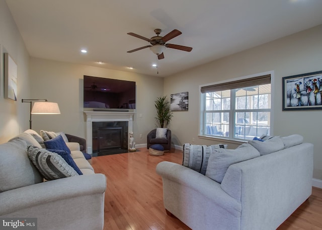 living area with wood finished floors, baseboards, recessed lighting, ceiling fan, and a tiled fireplace