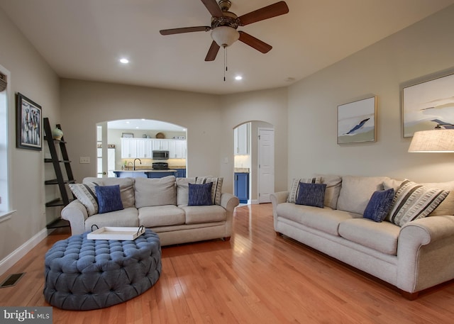 living room featuring recessed lighting, visible vents, arched walkways, and light wood finished floors