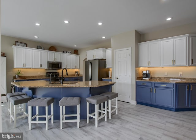 kitchen with blue cabinetry, recessed lighting, a sink, stainless steel appliances, and white cabinets