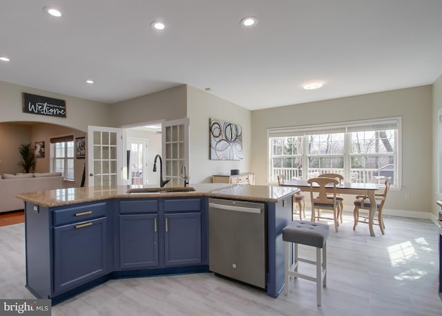 kitchen with recessed lighting, a kitchen island with sink, a sink, dishwasher, and open floor plan