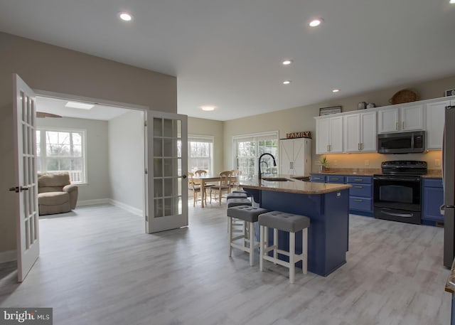 kitchen featuring stainless steel microwave, a kitchen bar, french doors, electric range, and blue cabinets