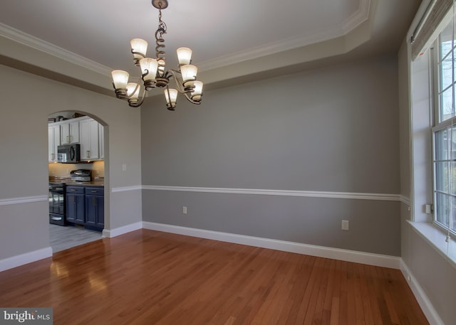 unfurnished room with arched walkways, crown molding, baseboards, and wood finished floors