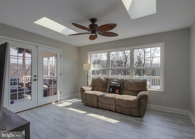 living area with a wealth of natural light, french doors, a skylight, and wood finished floors