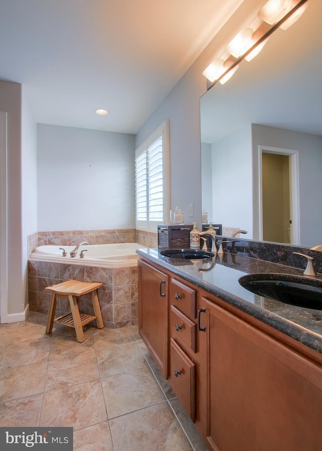 bathroom featuring tile patterned floors, double vanity, a garden tub, and a sink