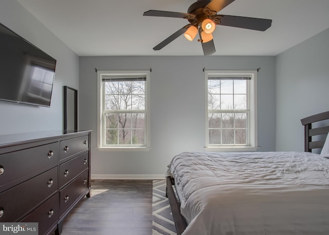 bedroom featuring dark wood finished floors, multiple windows, baseboards, and ceiling fan